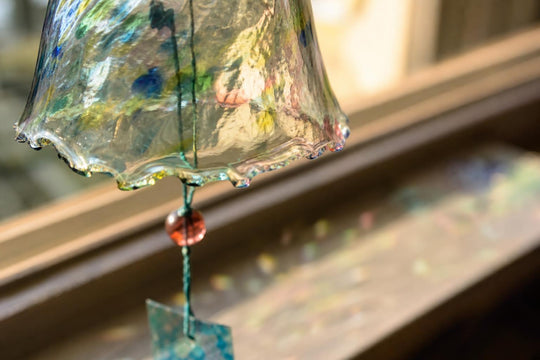 Macro detail of an unfinished glass rim on a wind chime, light passing through