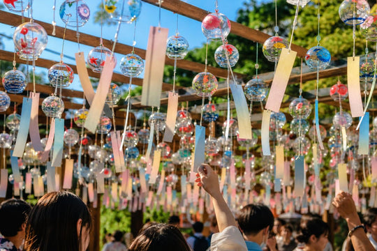 Rows of hand-painted glass wind chimes hanging together at an outdoor summer festival